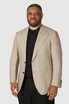 Man wearing a beige blazer over a black shirt on a white background